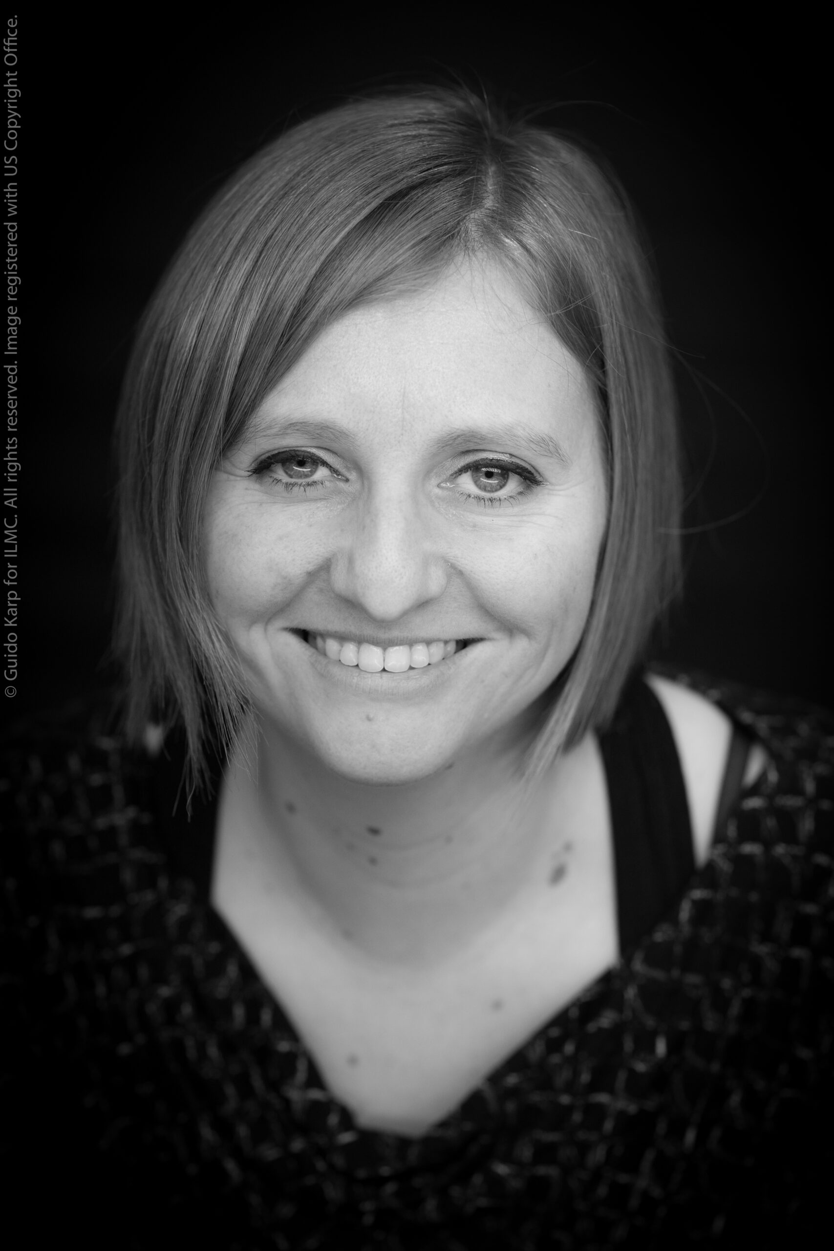 Black-and-white headshot of Sytske Kamstra, a white woman smiling, photographed by Guido Karp